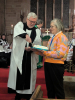 Harvey cutting a cake baked by his new parishioners with a ceremonial builder's trowel used to lay the foundation for the east window when the church was renovated in the 1800s